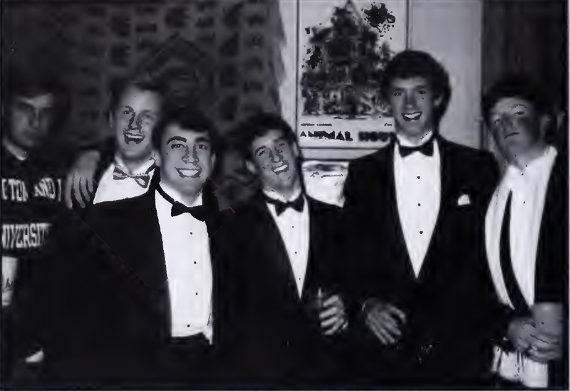 This is a photo from the Calyx 1989 of six W&L students during the 1989 Fancy Dress. All of the men are in tuxedos except one who is wearing a gray school crewneck sweater with Washington and Lee on the front.