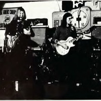 Two guitarists and a drummer from the Allman Brothers Band playing onstage