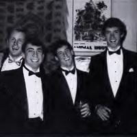 This is a photo from the Calyx 1989 of six W&L students during the 1989 Fancy Dress. All of the men are in tuxedos except one who is wearing a gray school crewneck sweater with Washington and Lee on the front.