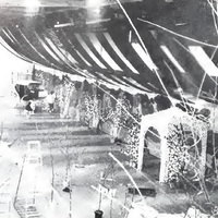 This is a black and white photograph of W&L's 1988 Fancy Dress: Reconciliation Ball venue. The photo includes decorated trees, an archway, a ceiling decor fixture, and a carriage.